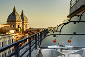 A balcony with a table set for two, overlooking a cityscape with domed buildings.