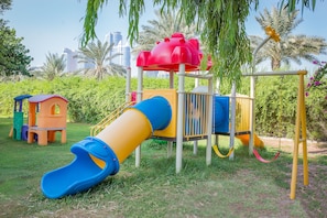 Un parque infantil con un tobogán, estructuras de escalada y columpios.