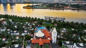 A coastal cityscape with a prominent mosque featuring a tall minaret, surrounded by residential buildings and a waterfront promenade. - Marbella Resort Sharjah (Sharjah)