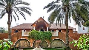 A courtyard with a fountain, palm trees, and a building with the sign "Marbella Resort Sharjah". - Marbella Resort Sharjah (Sharjah)
