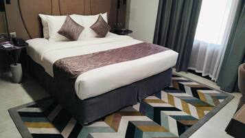 A hotel room with a large bed, a bedside table with a lamp, and a patterned rug.
