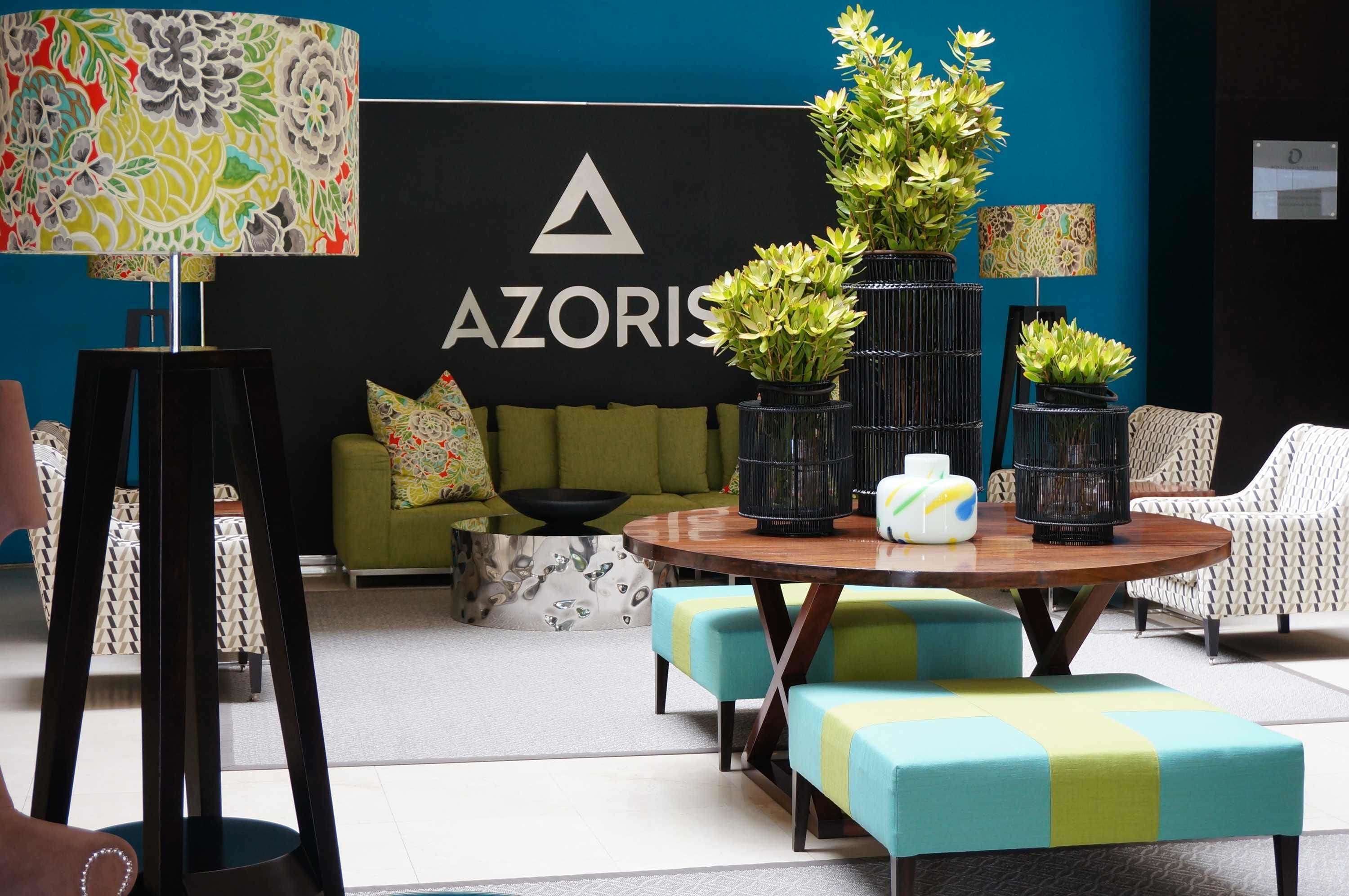 A modern lounge area with a sofa, round table, and potted plants.