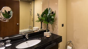 A modern bathroom with a black sink, a mirror, and a potted plant.