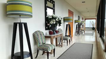 Un pasillo con una zona de comedor que incluye sillas estampadas, una mesa de madera y una planta en maceta.