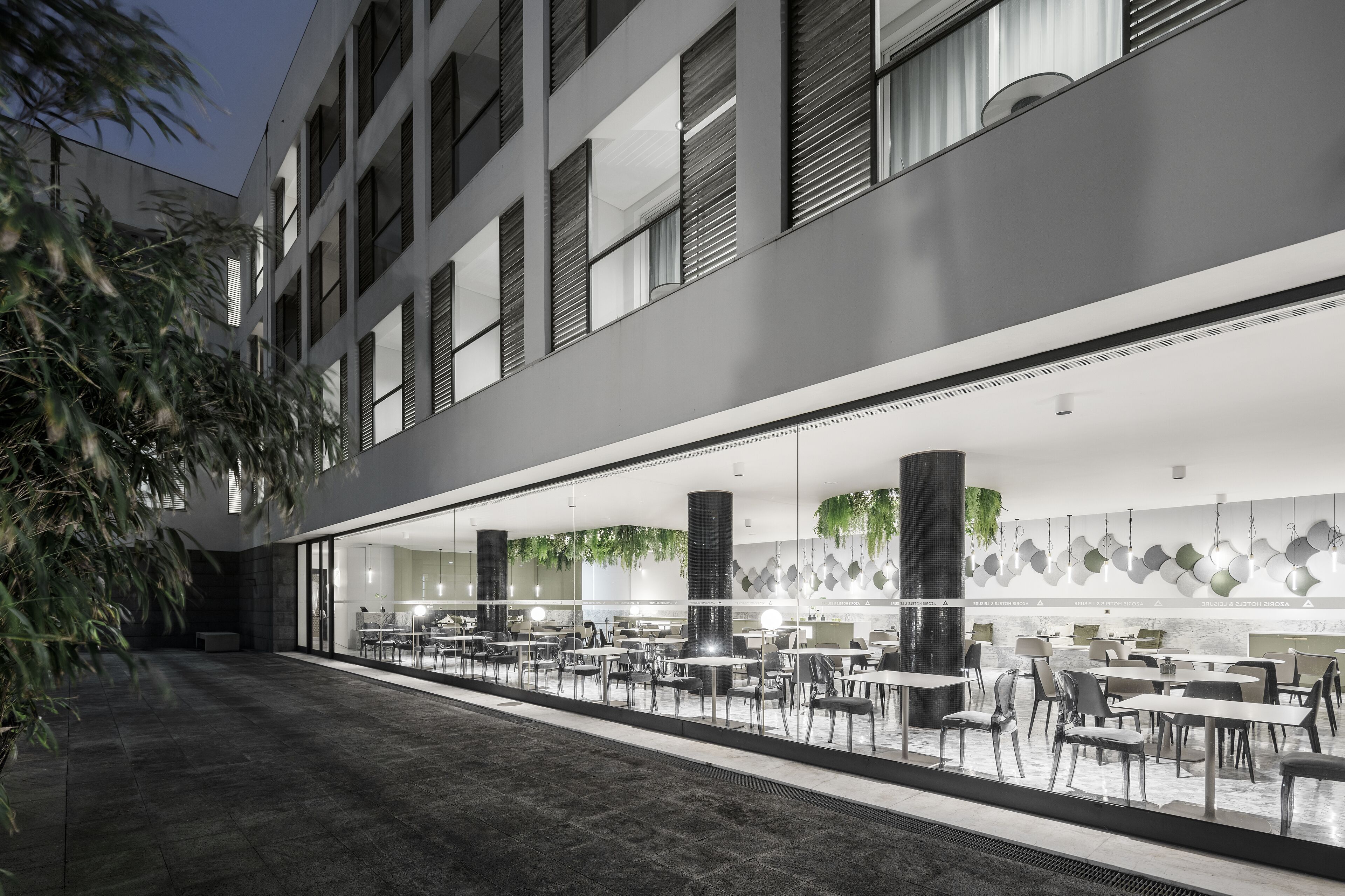 A modern hotel lobby with a long reception desk, multiple seating areas, and a large glass wall.