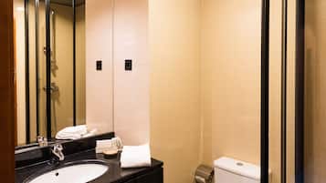 A modern bathroom with a black sink, white toilet, and a glass shower enclosure.