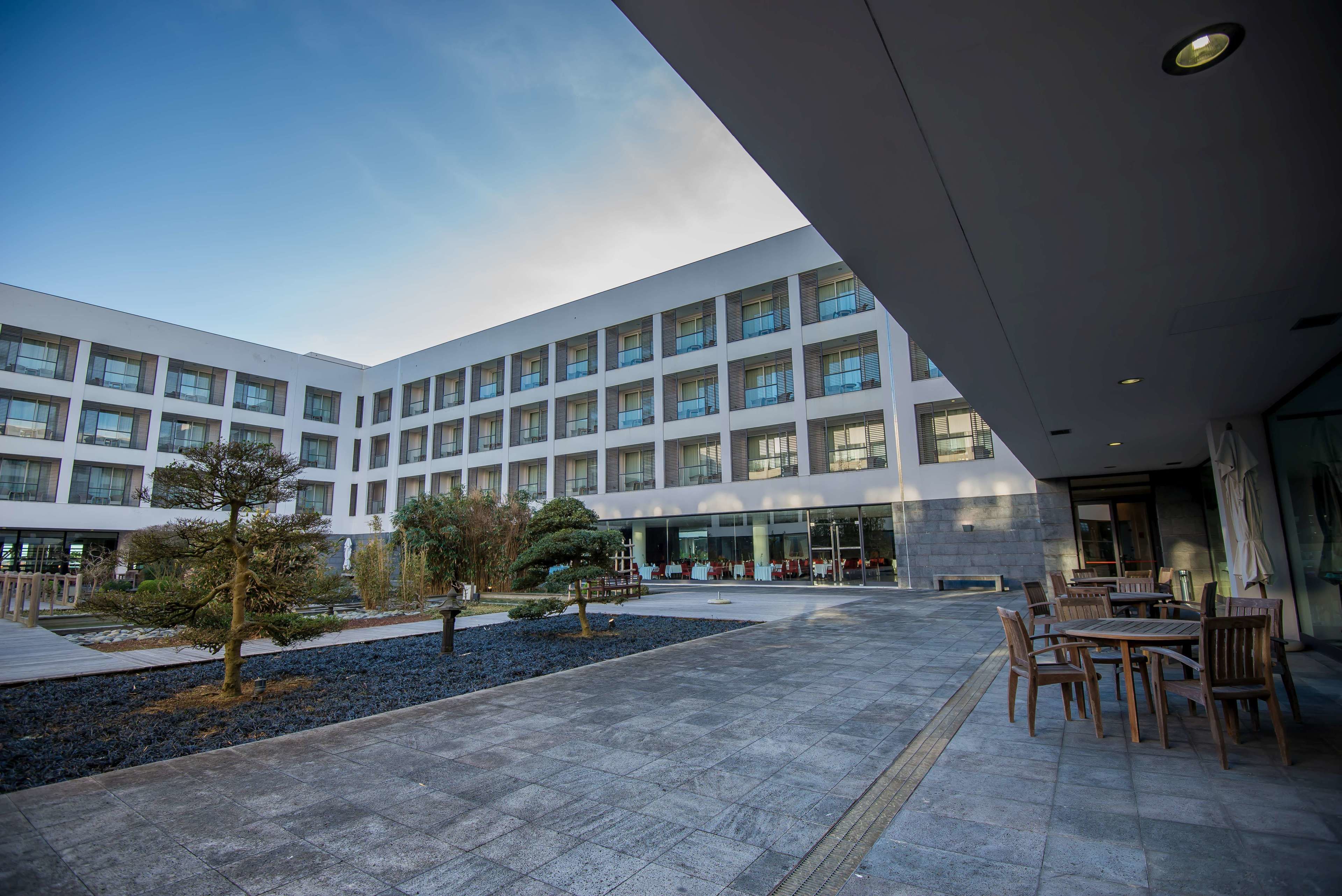 A modern building with a courtyard, outdoor seating area, and a clear sky.