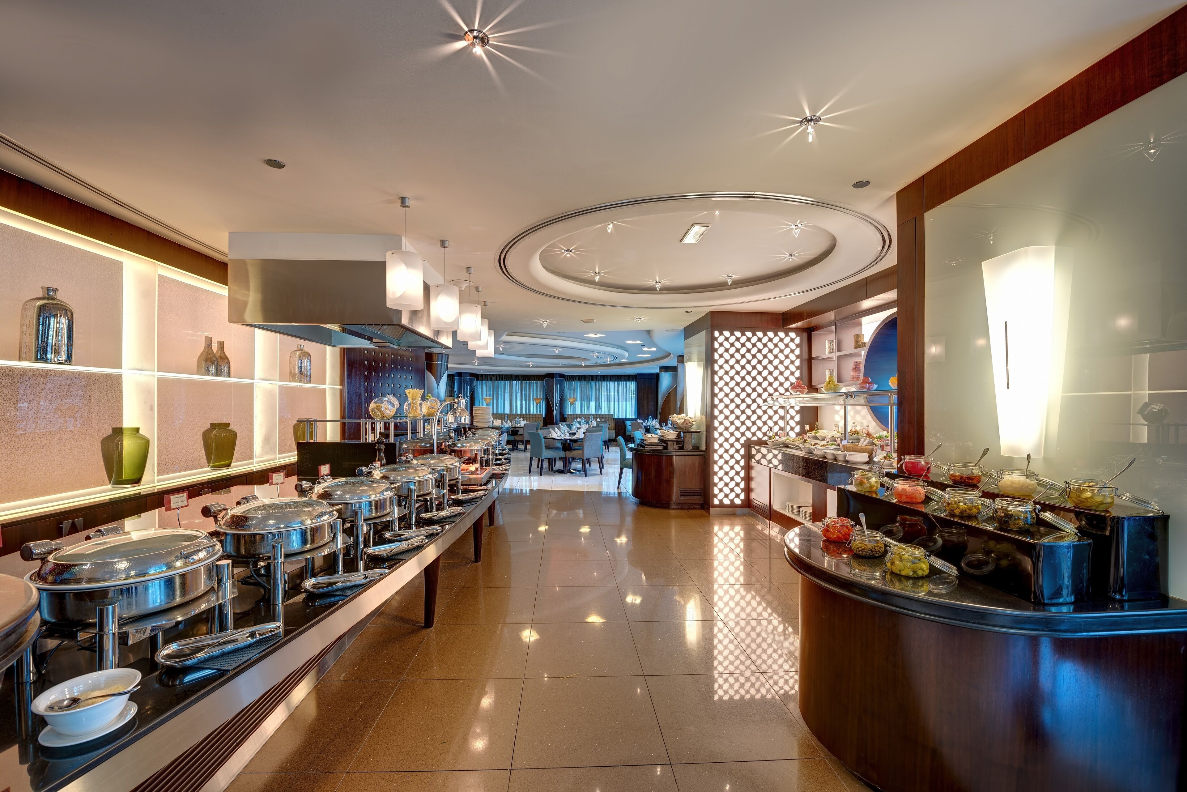 A buffet area with multiple serving stations, a long counter, and a seating area in the background.