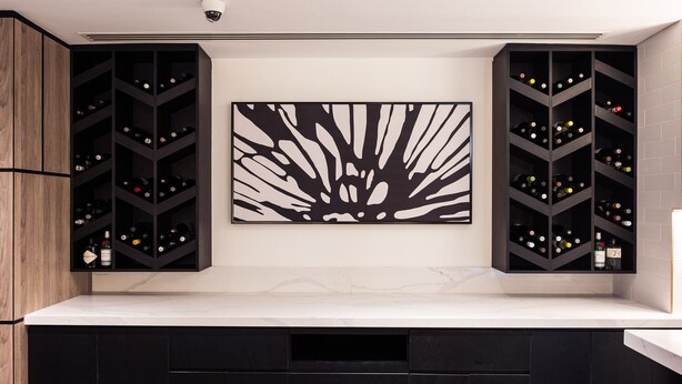 A modern kitchen with black cabinetry, a marble countertop, and a large abstract painting above the cabinets. - Rose Rayhaan by Rotana (Dubai)