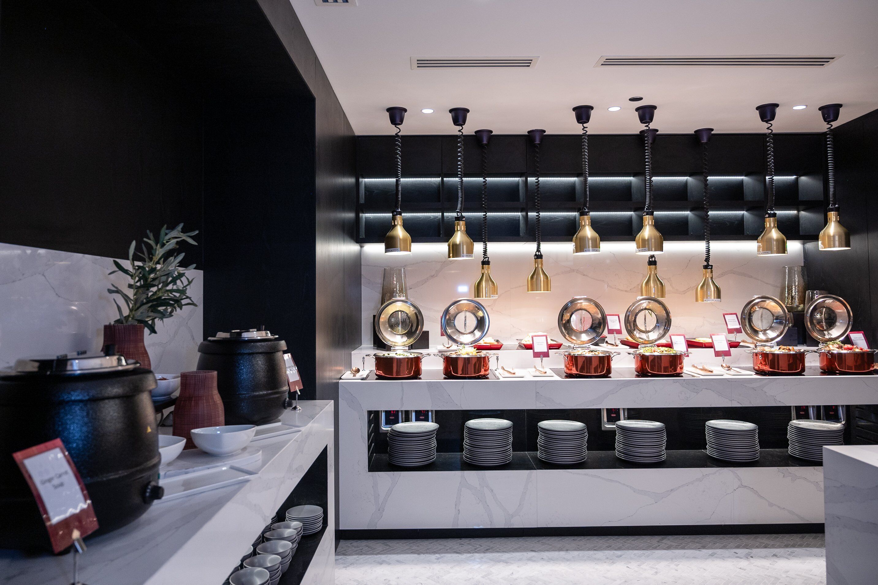 Montaje tipo buffet con múltiples estaciones de servicio, incluyendo platos y tazones, y una variedad de utensilios de cocina.