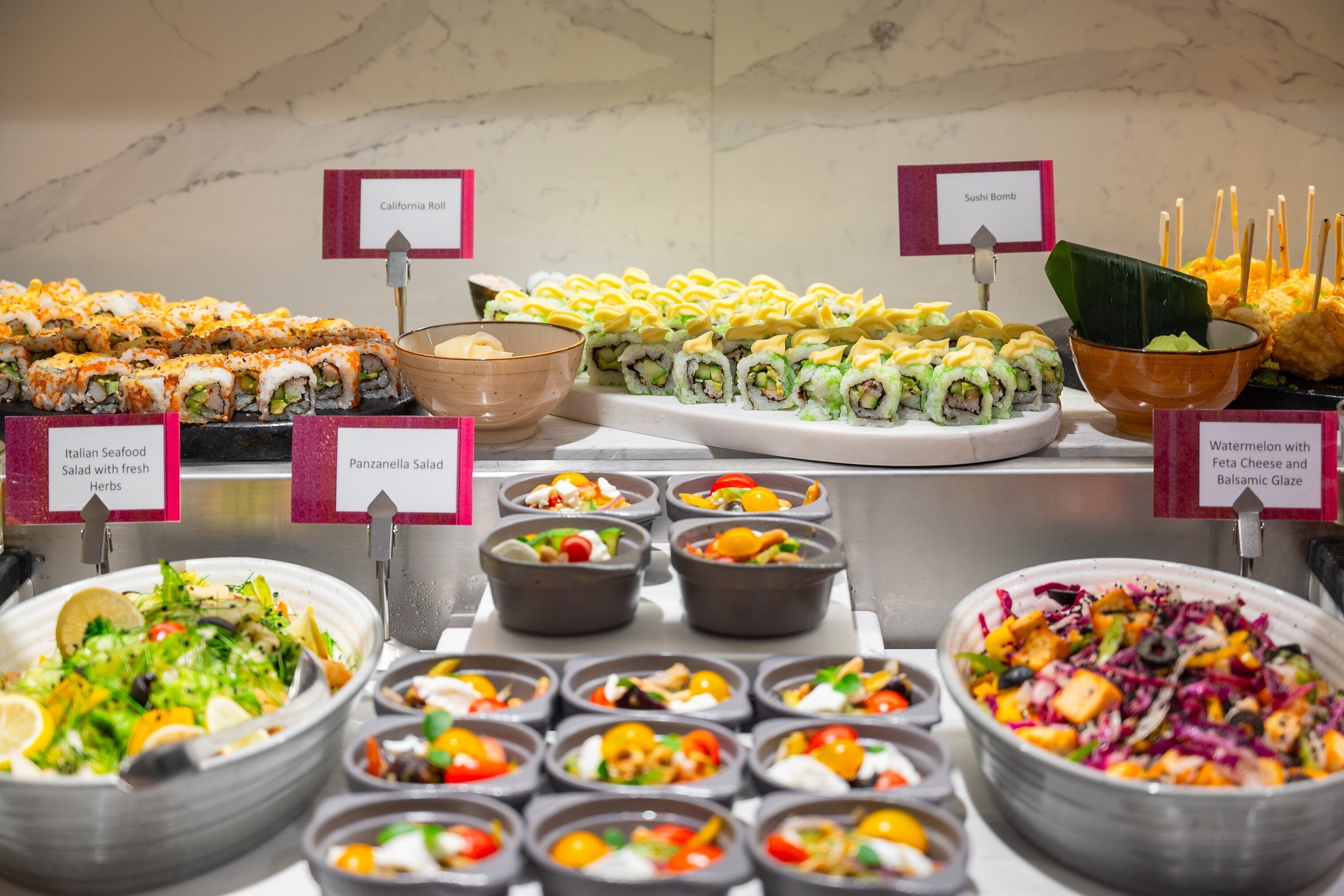 A buffet with various dishes including sushi, salads, and bowls of food.