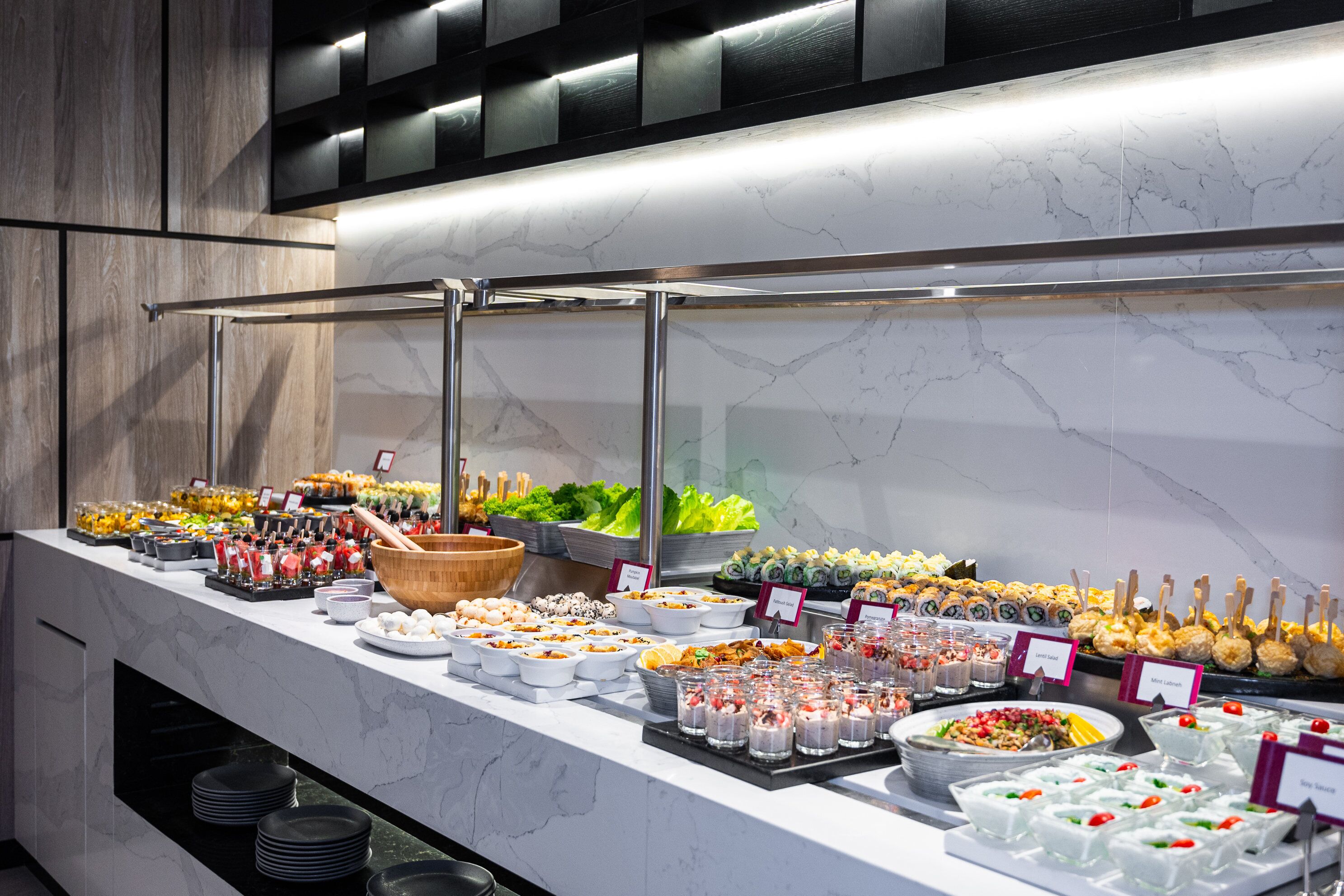 Een buffet met diverse gerechten en drankjes, waaronder sushi, salades en desserts.