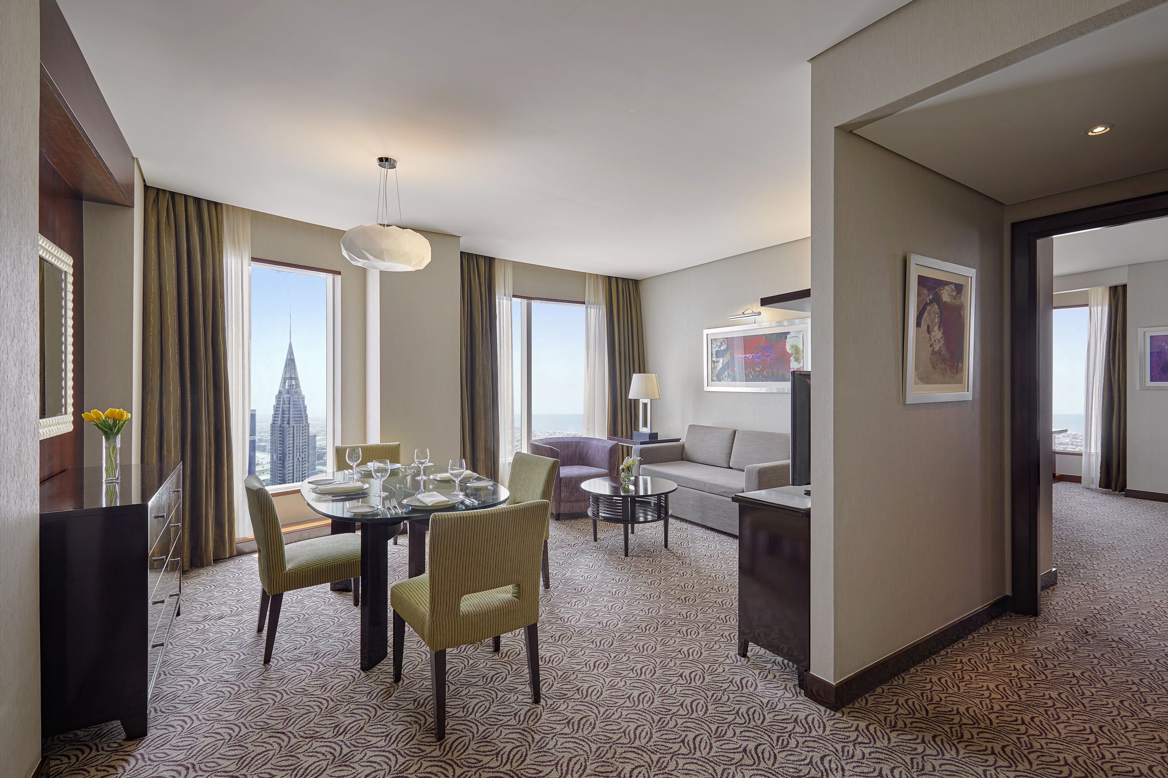 Habitación de hotel con comedor, sofá y vista a la ciudad.