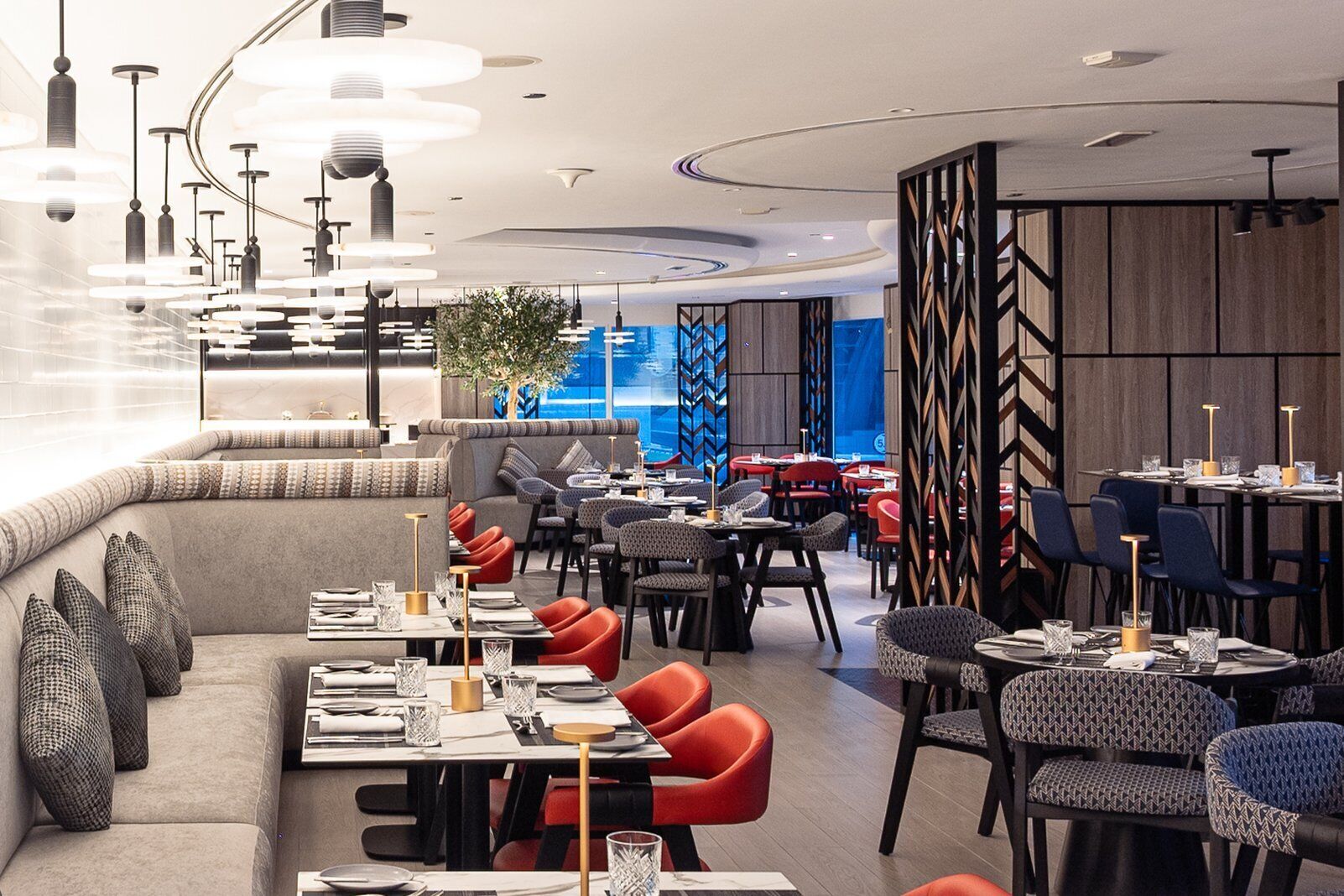 A modern restaurant with a mix of seating options including tables and a sofa area.