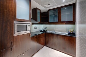A modern kitchen with wooden cabinets, a stainless steel microwave, and a sink.