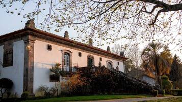 Traditional building with a central entrance and decorative windows, set amidst a well-maintained garden.