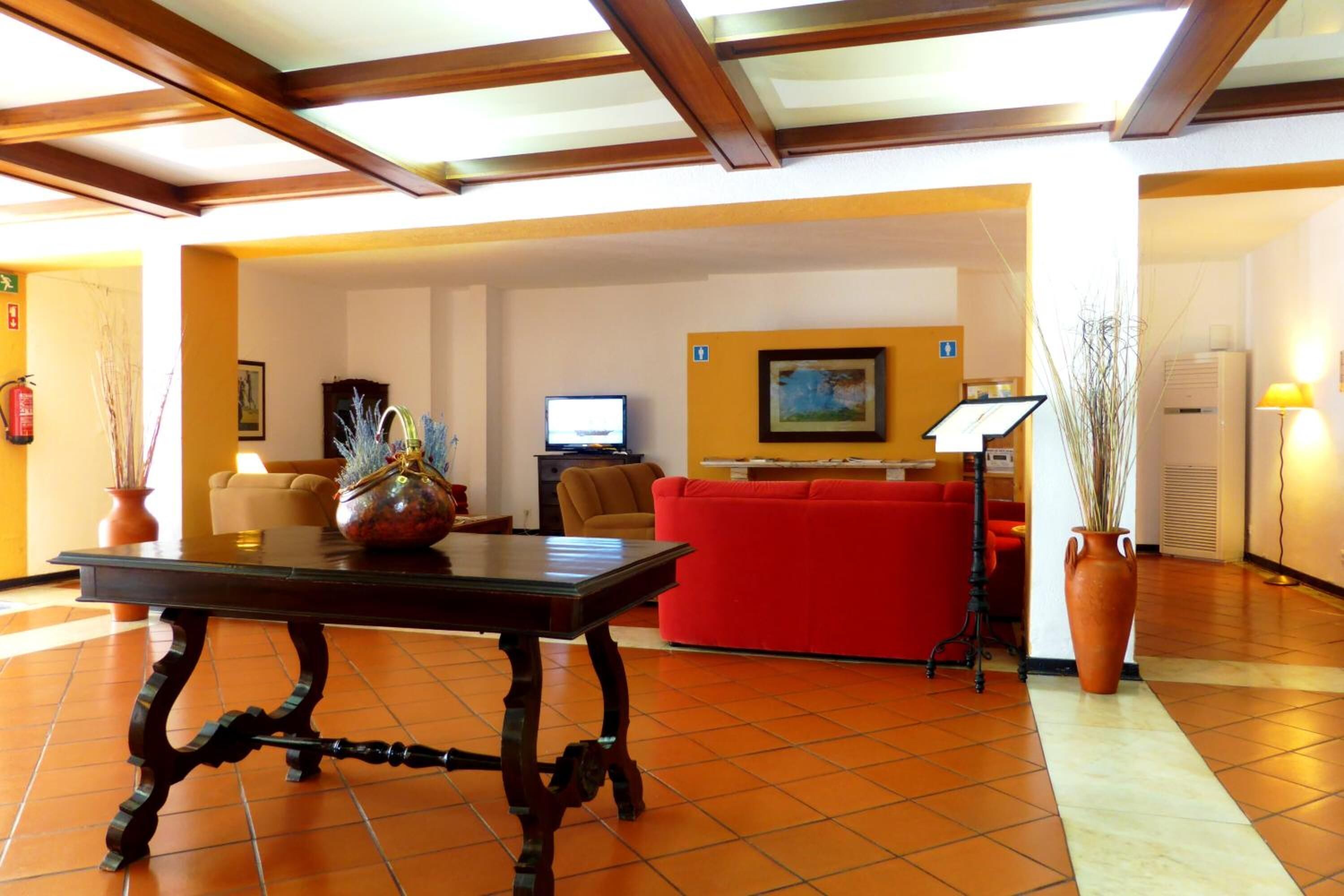 Un vestíbulo con una mesa de madera, un sofá rojo y un televisor.