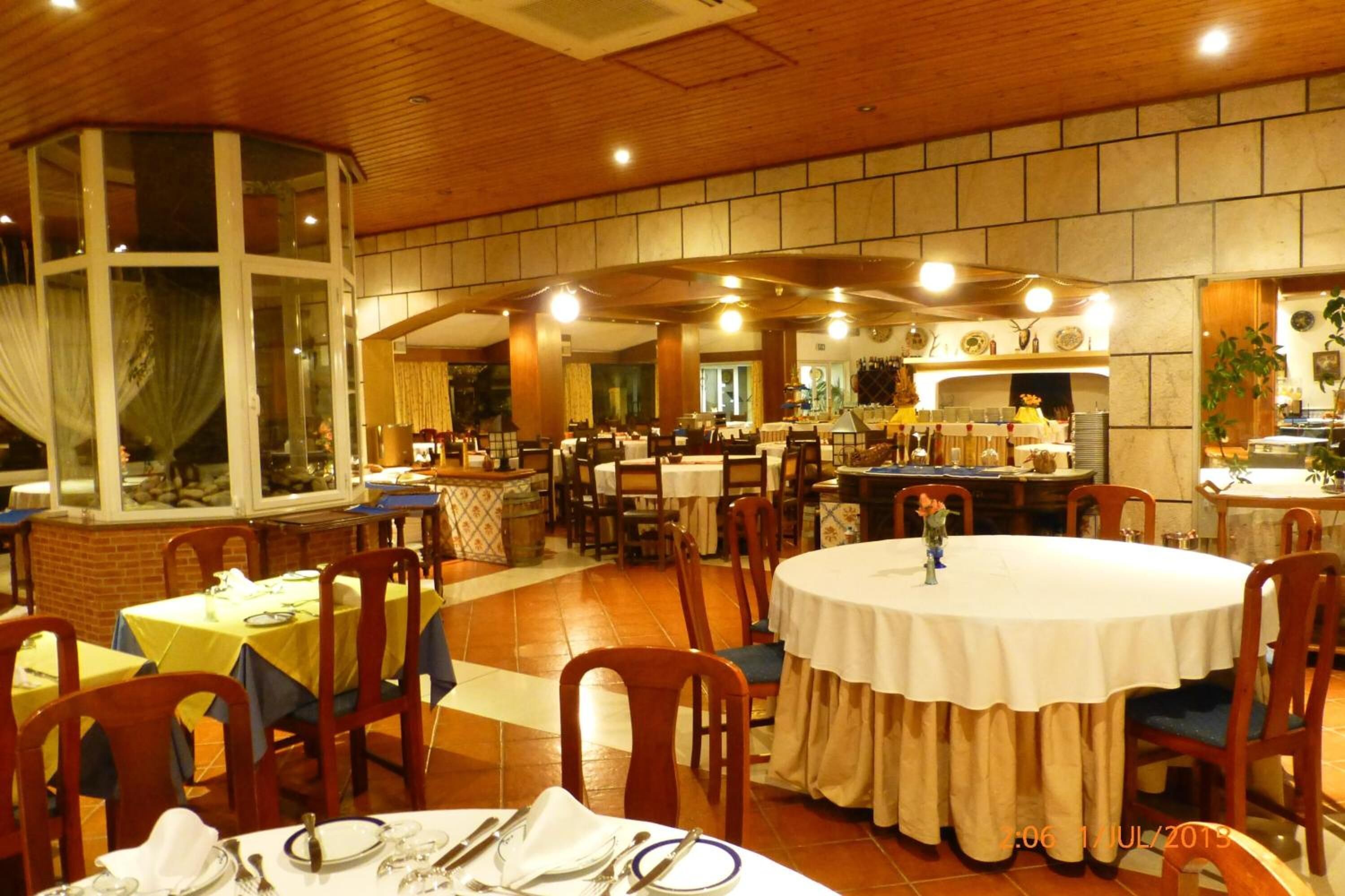 A restaurant with round tables, wooden chairs, and a brick wall.