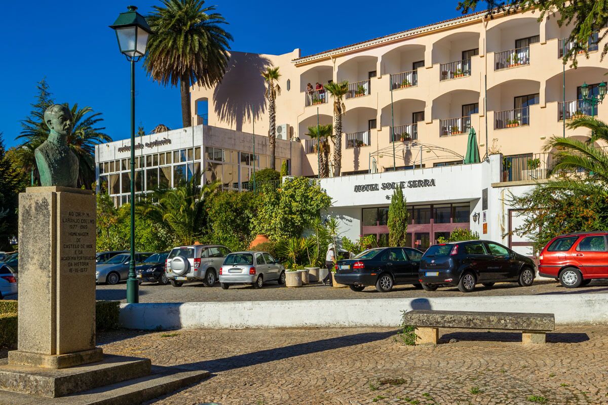 Un hotel con un letrero que dice "HOTEL SOLERA", que presenta una fachada moderna con balcones y un estacionamiento con varios coches.