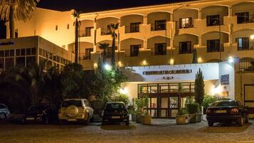 Un hotel con fachada blanca, varios balcones y un letrero que indica que es un hotel.