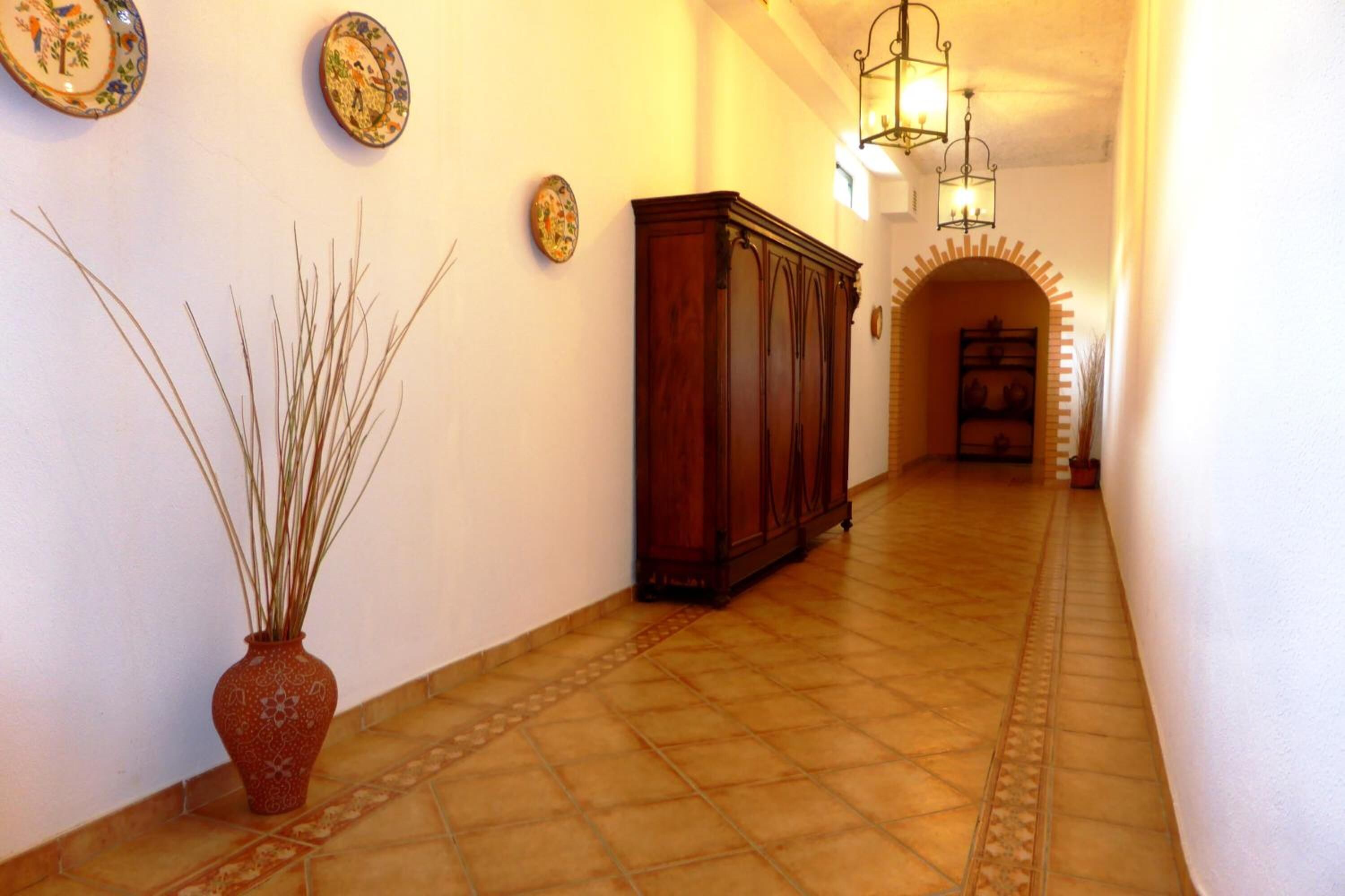 A hallway with a tiled floor, a wooden cabinet, and wall-mounted decorative plates.