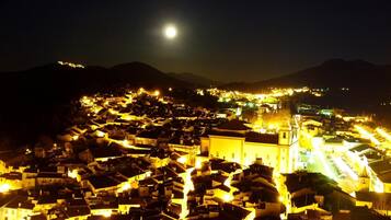 Vista nocturna de un pueblo con edificios iluminados y una iglesia destacada.