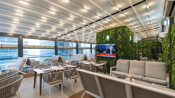 A modern lounge area with seating, a TV screen, and a green wall. - Samaya Hotel Deira (Dubai)