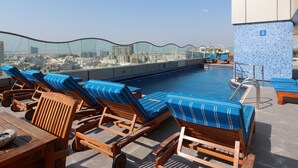A rooftop pool area with lounge chairs and a city view. - Samaya Hotel Deira (Dubai)