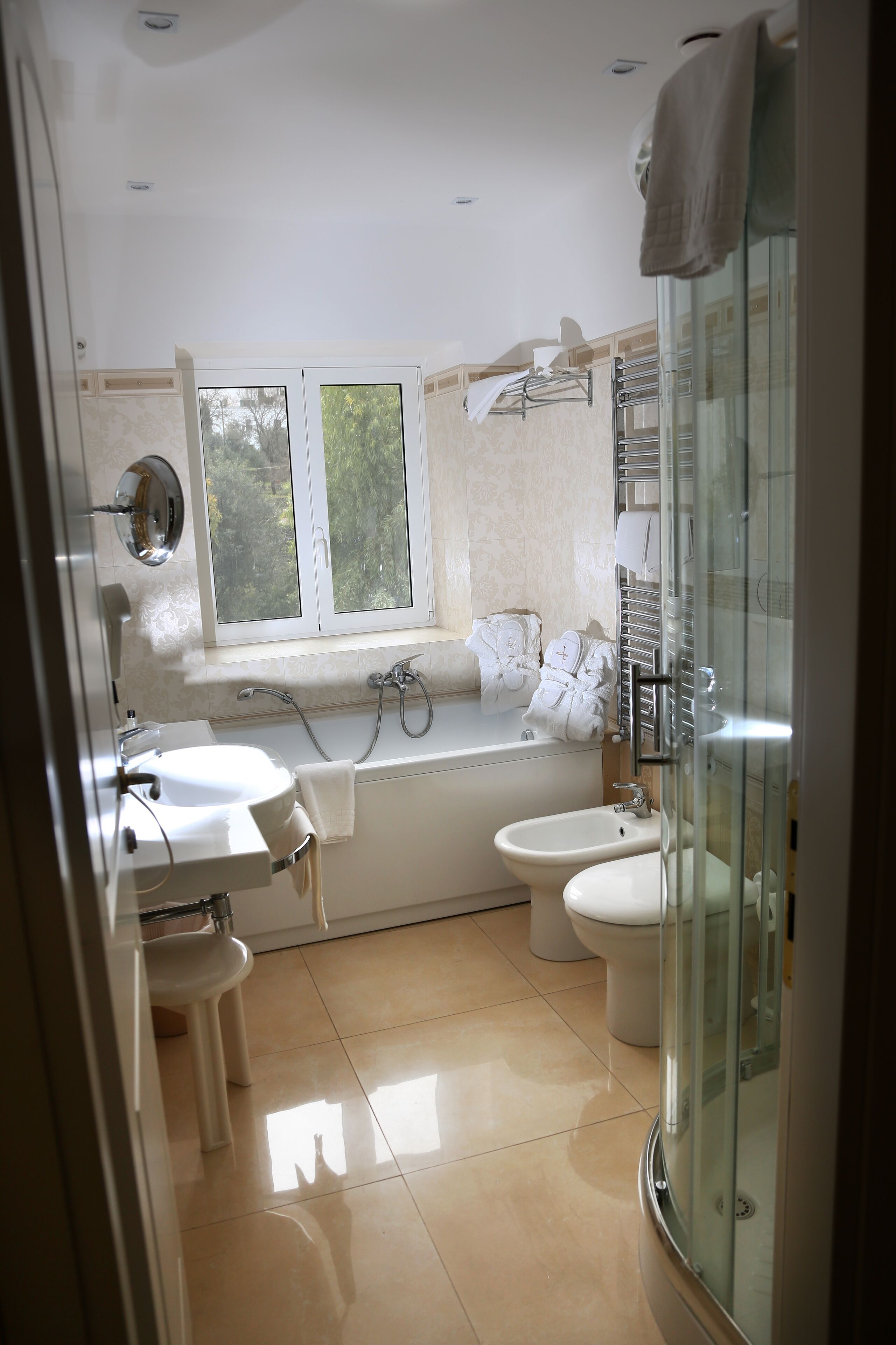 A modern bathroom with a bathtub, two sinks, a toilet, and a glass shower enclosure.