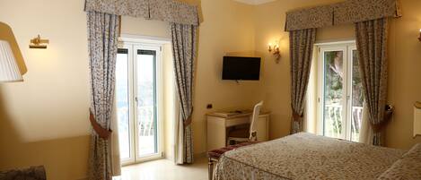 A hotel room with a bed, a desk, a chair, a TV, and curtains.