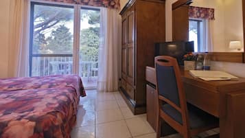 A hotel room with a bed, a desk, a chair, a television, and a window with curtains.