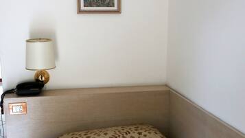 A hotel room with a bed, a bedside lamp, a telephone, and a framed picture on the wall.