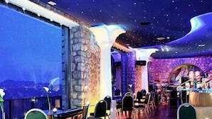 A restaurant with a stone wall, wooden tables, and chairs. - Hotel San Michele (Anacapri)