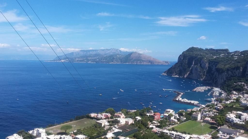 A coastal town with a marina, buildings, and a prominent cliff.