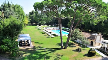 Relax in a serene poolside setting surrounded by lush greenery and a shaded pavilion.