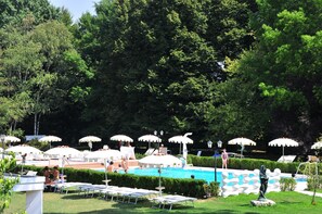 A pool area with lounge chairs and umbrellas, surrounded by trees. - Park Hotel Villa Giustinian (Mirano)