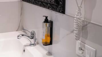 A bathroom with a white sink, a black ornate mirror, and a white hairdryer mounted on the wall.