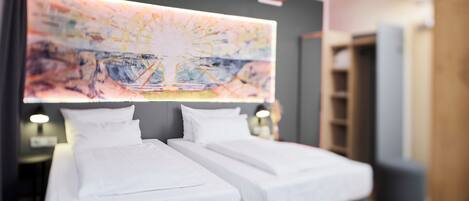 Habitación de hotel con dos camas, un cuadro abstracto grande en la pared y techo de madera.
