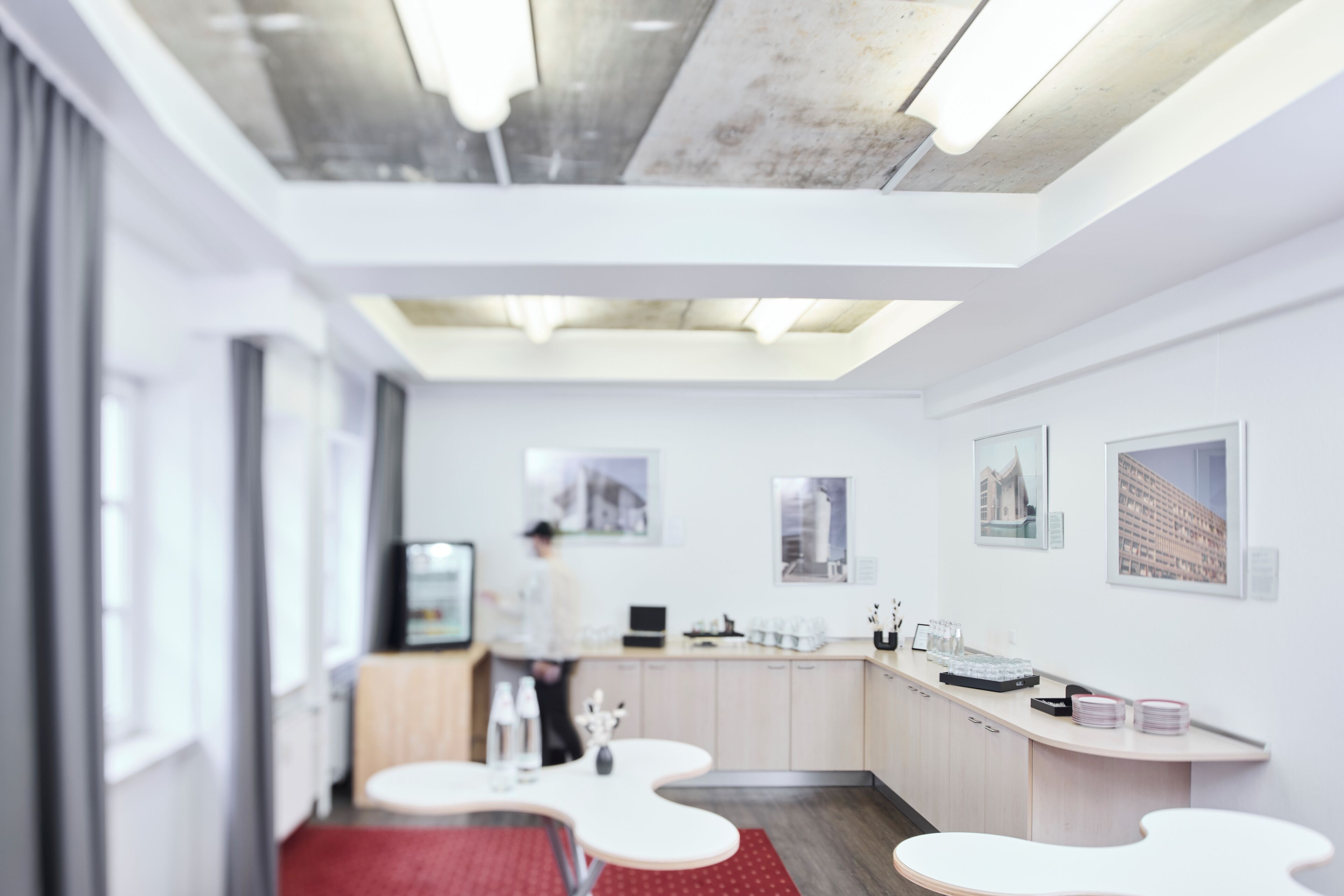 A modern hotel room with a kitchenette, a dining area, and a seating space.
