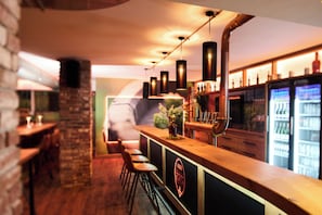 Zona de bar con mostrador de madera, taburetes y grifo de cobre.