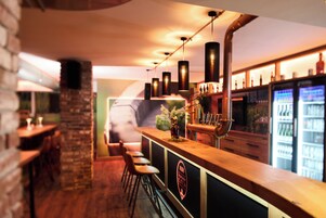 Zona de bar con mostrador de madera, taburetes y grifo de cobre.