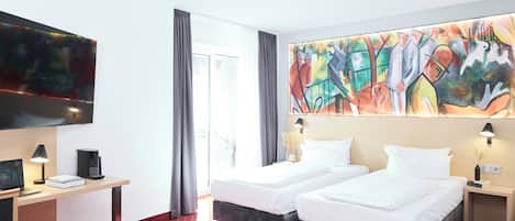A hotel room with two beds, a desk with a computer, a TV, and a large abstract painting.