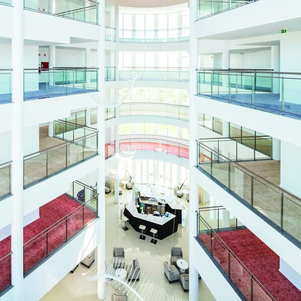 Ein mehrgeschossiges Atrium mit Glastrennvorrichtungen, einer zentralen Sitzgelegenheit und einer Teppichstufenhaus.