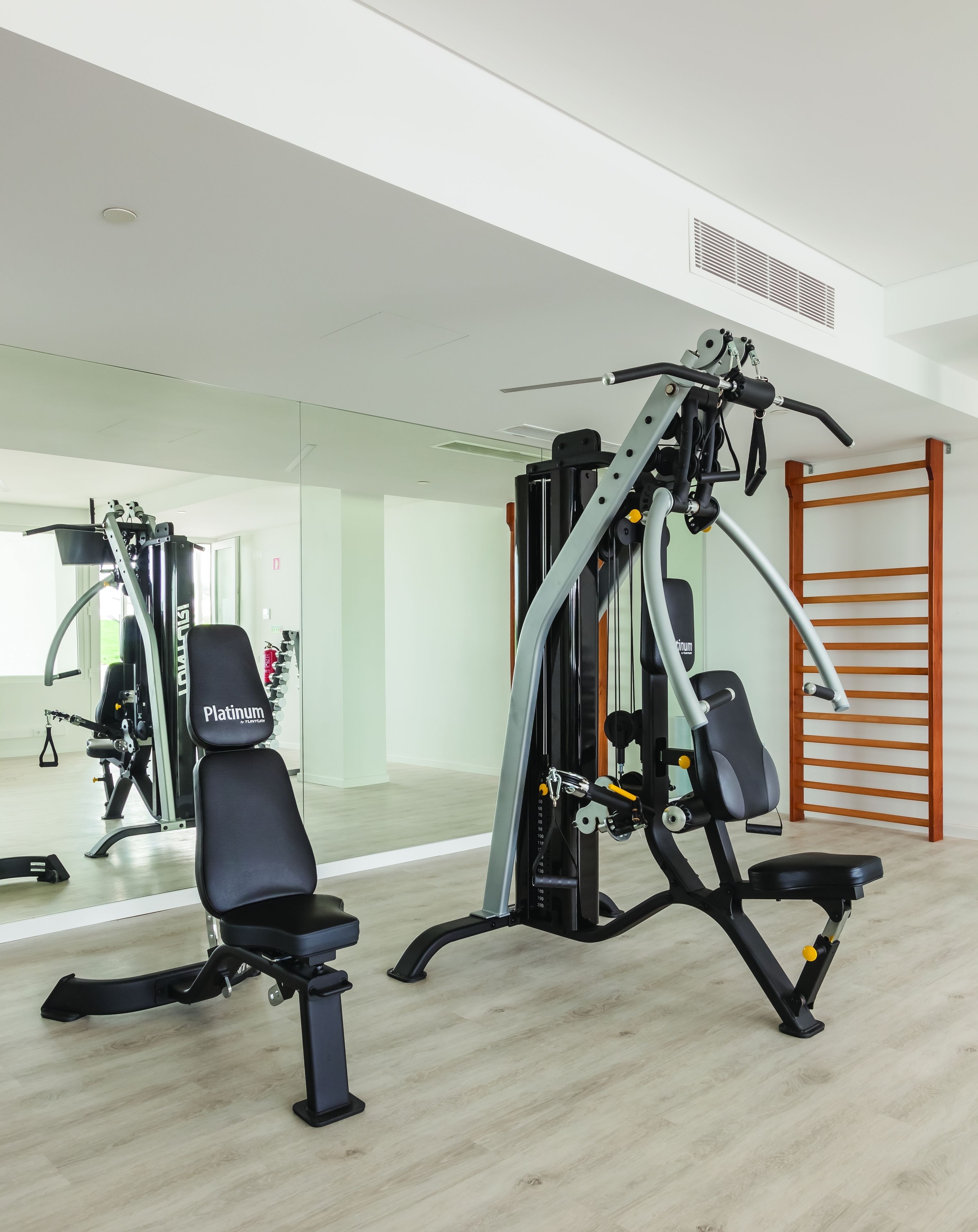 A gym with exercise equipment, a mirror, and a wooden ladder.