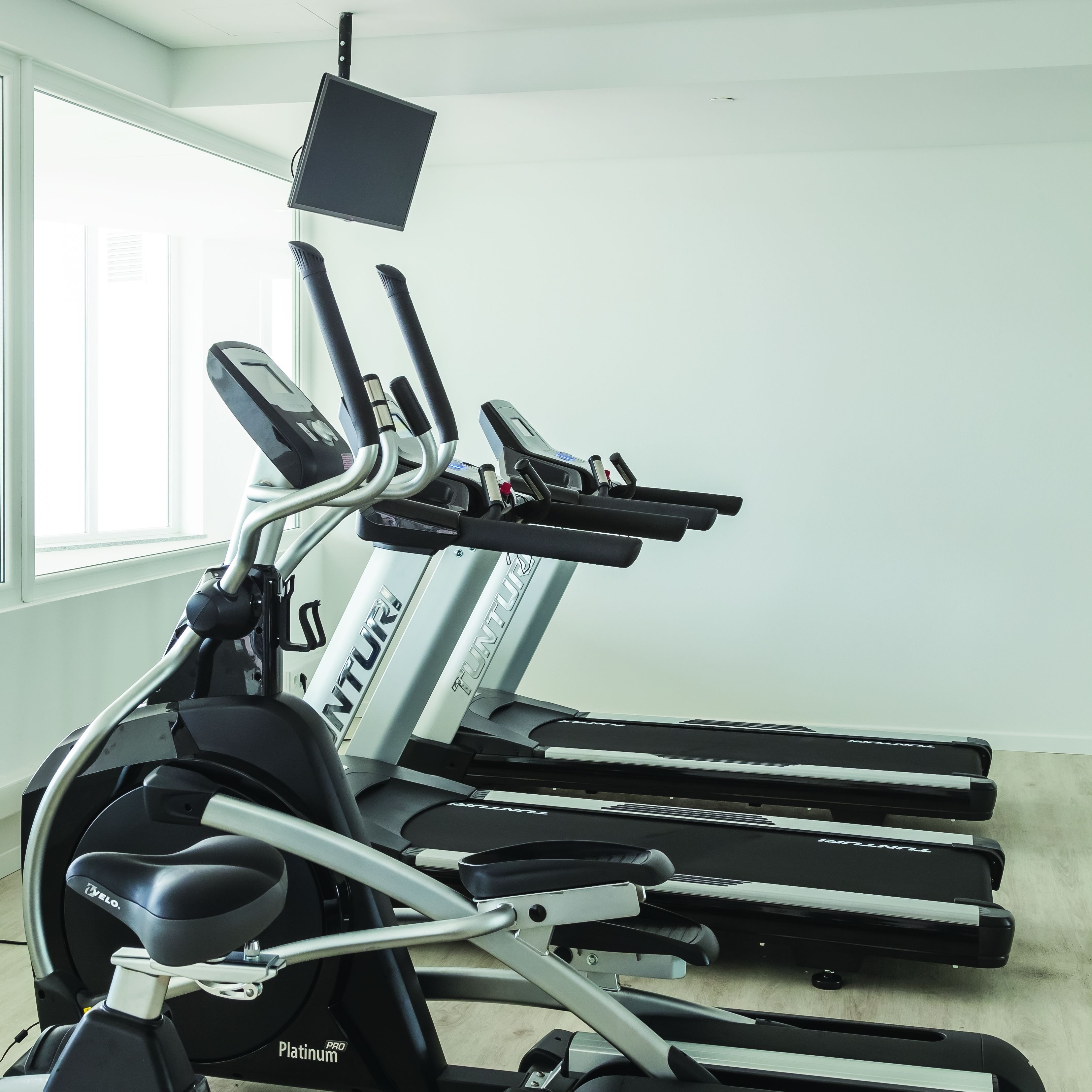 A row of treadmills in a room with a large window.