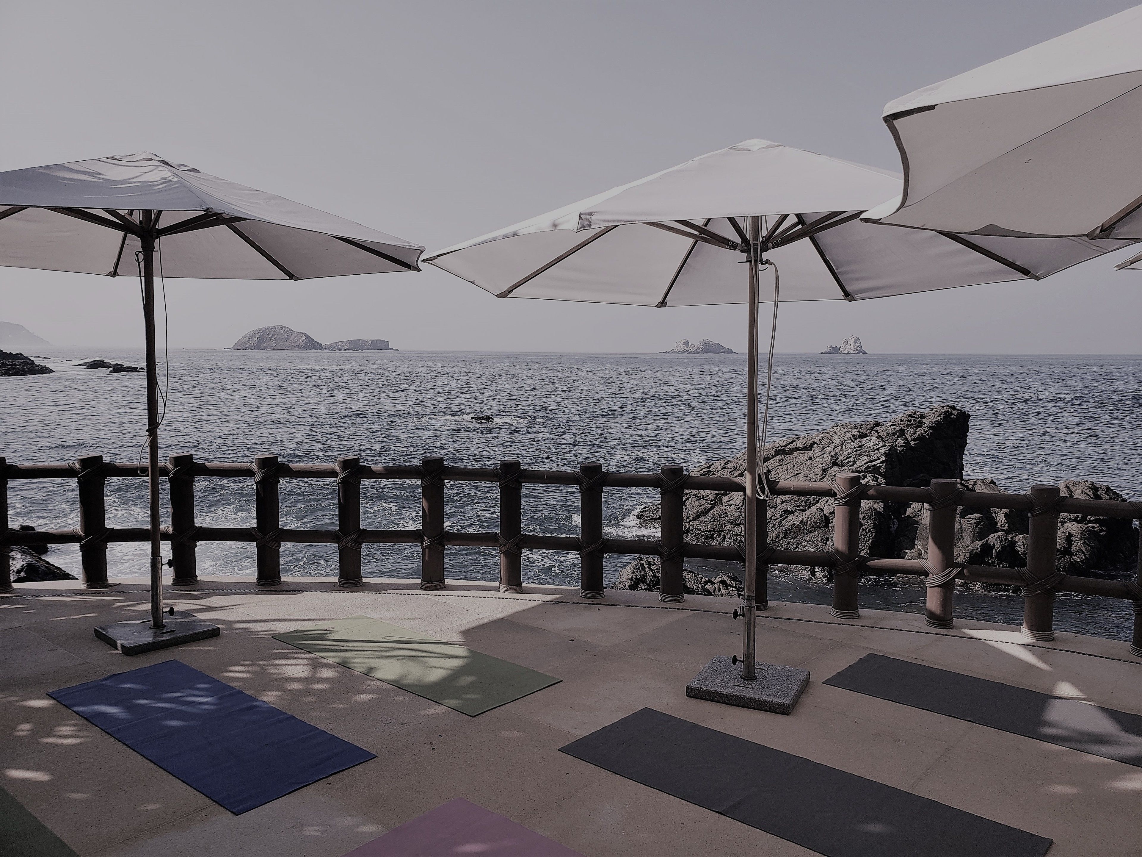 A seaside patio with exercise mats and umbrellas.