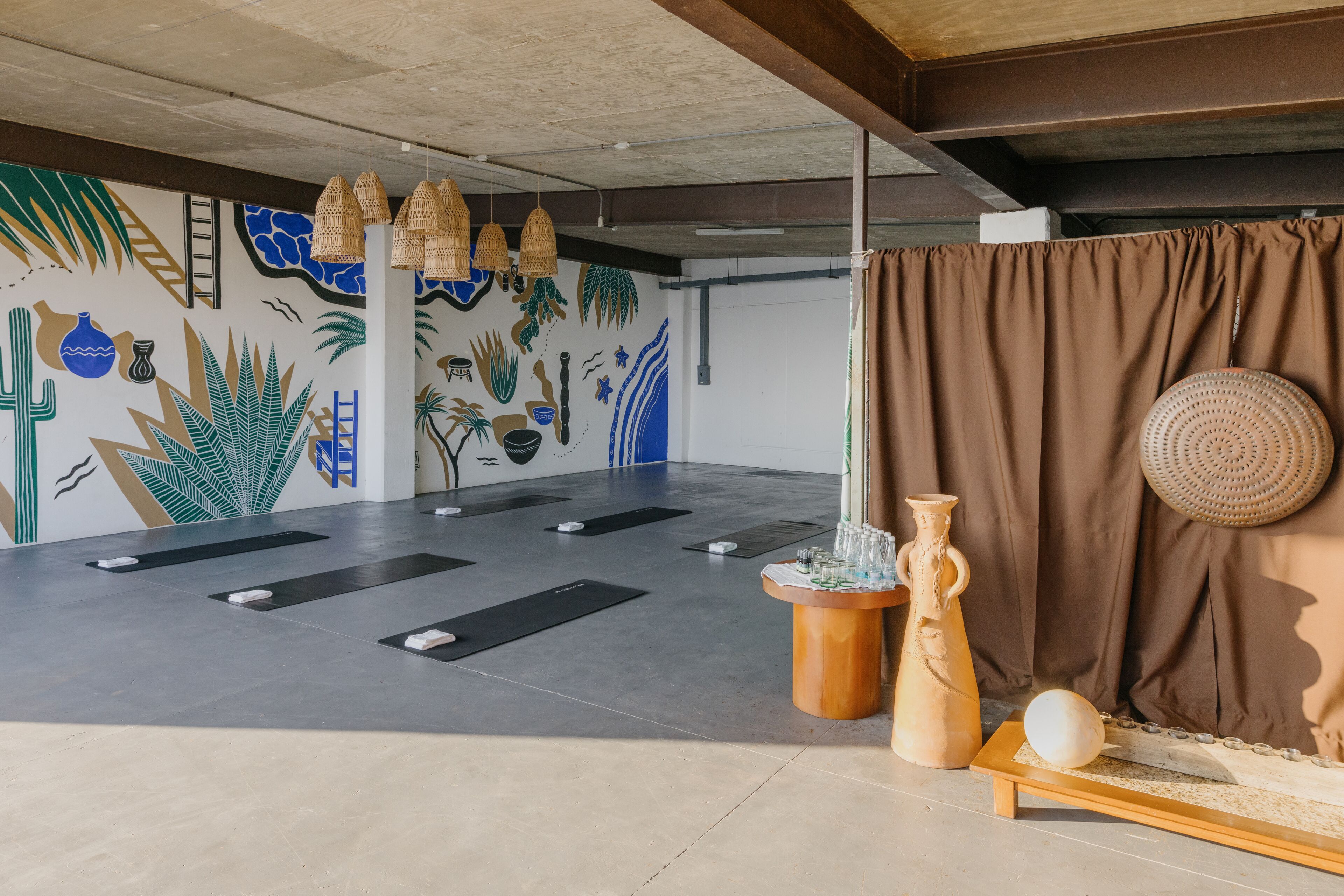 A spacious room with a large wall mural, exercise mats, and a small table with decorative items.