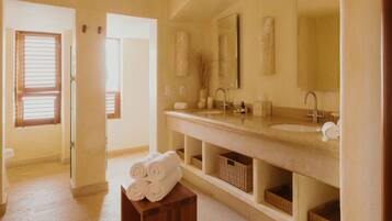 Un baño con un lavamanos grande, un espejo y dos cestos debajo del mueble.