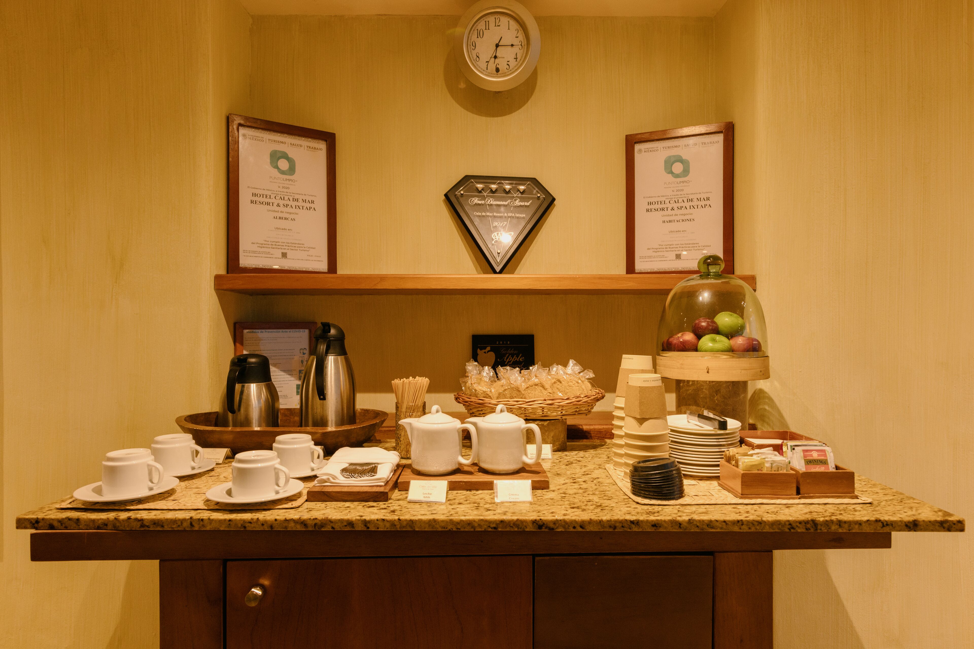 A breakfast buffet setup with coffee makers, tea pots, and fruit display.