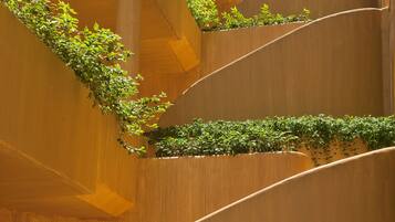 A modern building with curved balconies and green plants.
